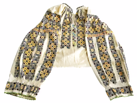 Camicia tradizionale in seta panna (ie), con maniche riccamente ricamate con motivi geometrici neri e gialli.