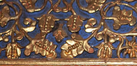 Detaliu de sculptură aurită pe fond albastru: flori și boboci.